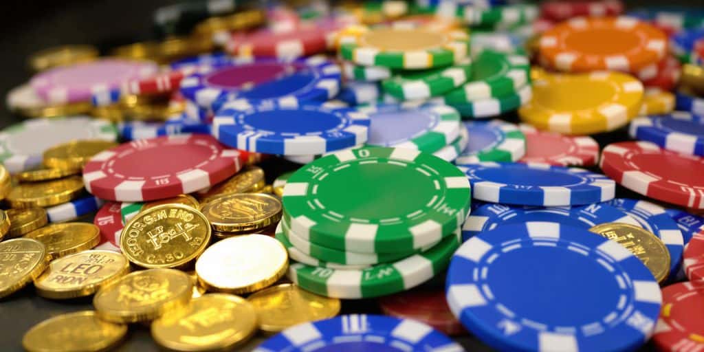 Stack of chips and coins with slot machine.
